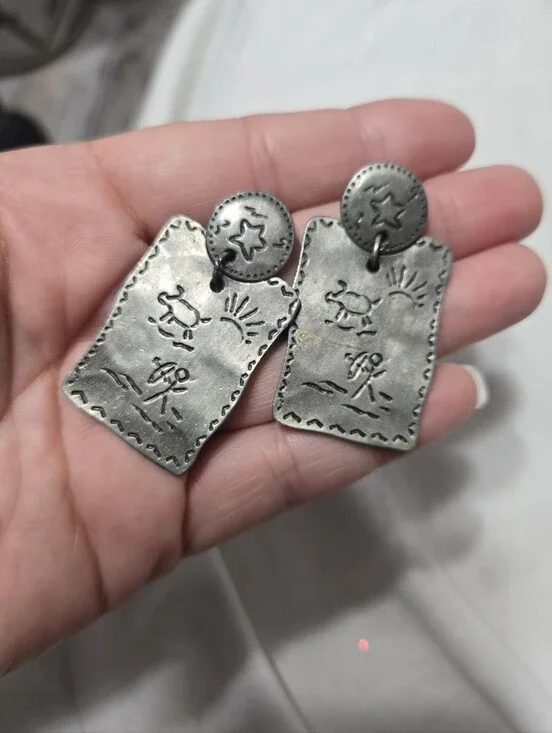 Vintage silver-tone drop earrings featuring embossed Southwestern petroglyph