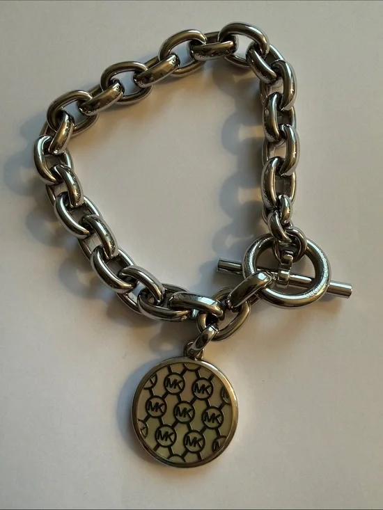Michael Kors Silver-tone Toggle Bracelet with Dual Sided Logo Charm.
