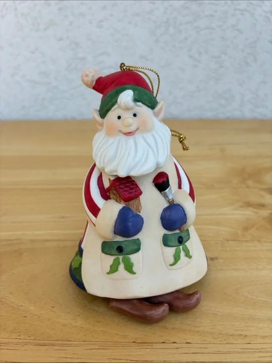 Ceramic elf painting a bird house bell ornament with little floppy legs