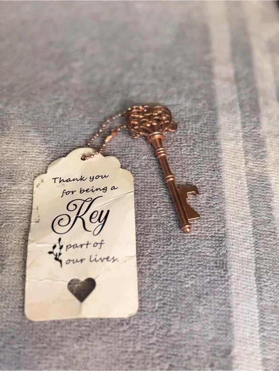 Gold tone Key-shaped pendant with card.