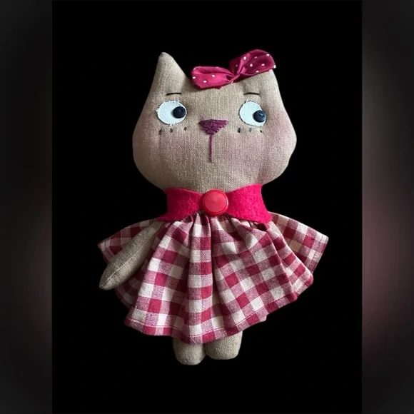 Handmade cloth cat doll in a red and white plaid dress.