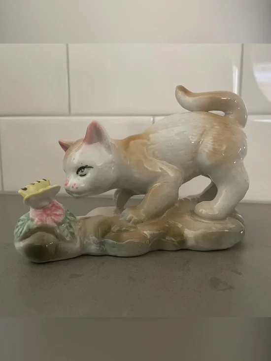 Vintage porcelain cat figurine playing with a butterfly.
