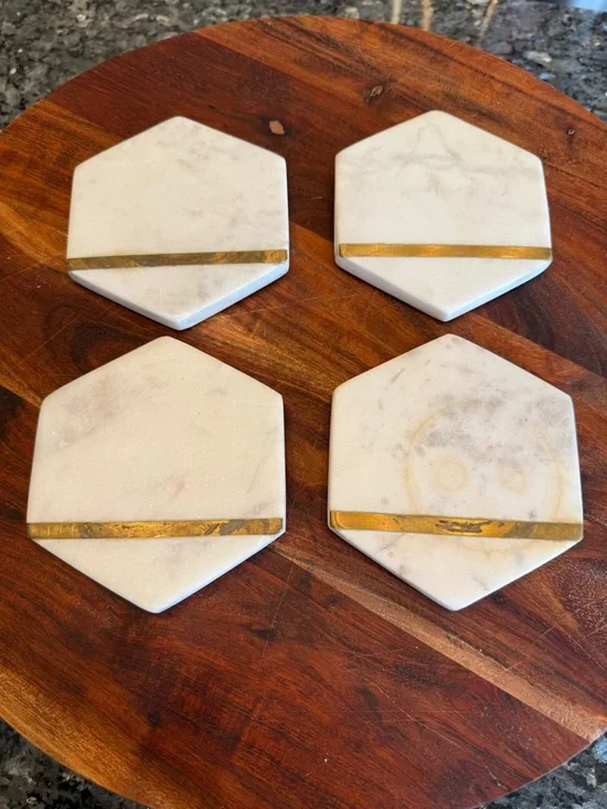 Hexagonal white marble coasters featuring a brass inlay design