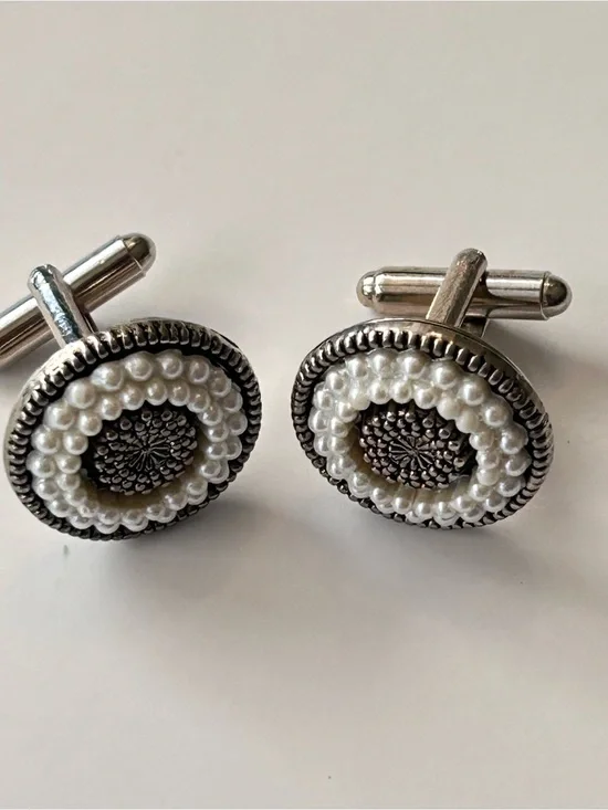 Cufflinks featuring white imitation pearls set in silver-tone, textured border.