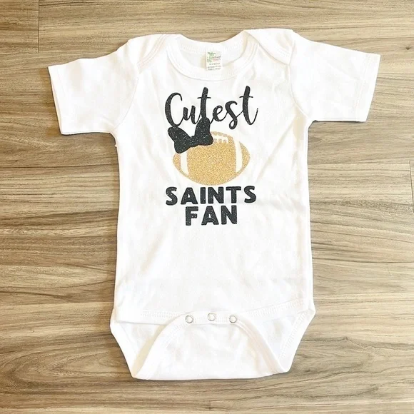 Laughing Giraffe Cutest Saints Fan black/gold glitter baby bodysuit
