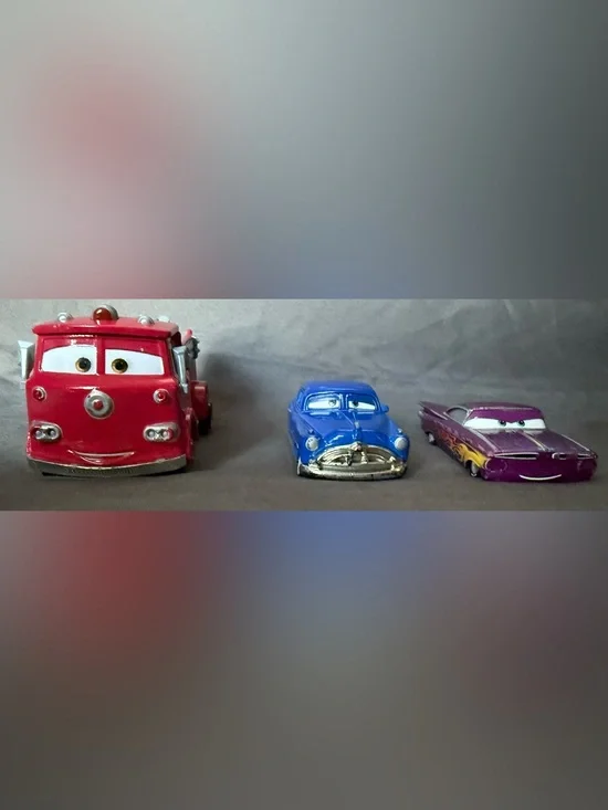 Disney Pixar Cars Diecast: Red Fire Truck, Doc Hudson, and Purple Ramon.