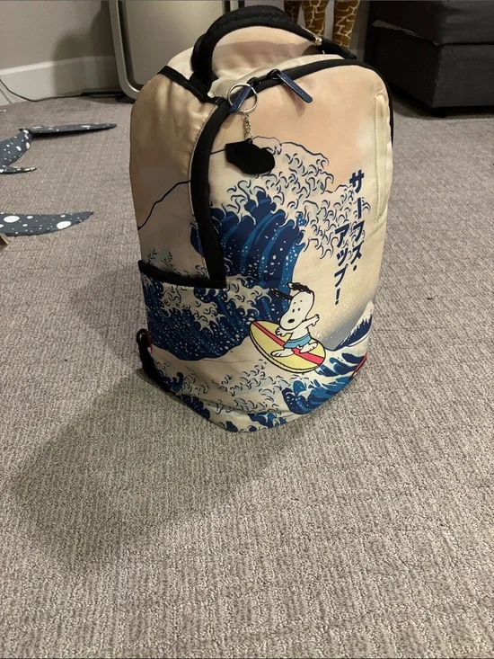 Sprayground Beige Backpack with Blue Wave and Surfing Cartoon