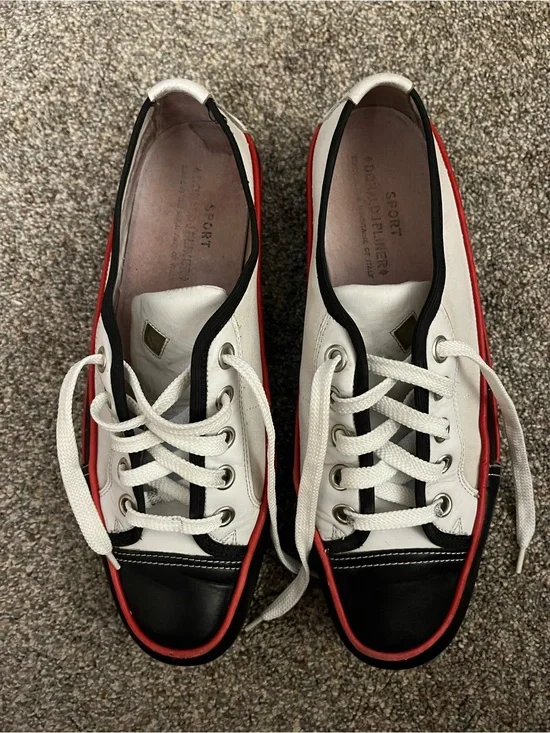 Donald J Pliner white canvas and black leather sneakers with red trim.