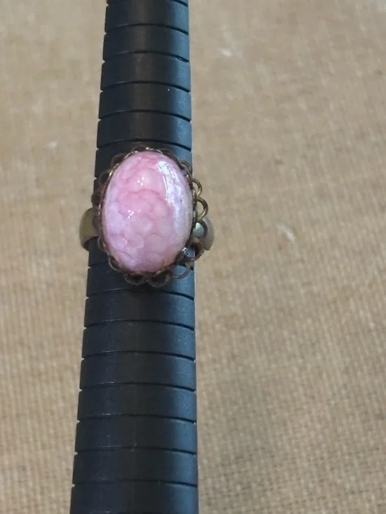 Pink cabochon stone set in an ornate, antiqued brass filigree setting Adjustable