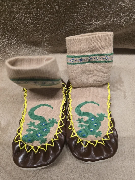 Konfetti Swedish Moccasins feature a beige sock top with a green lizard design