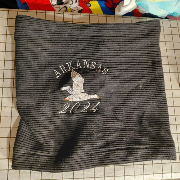 black neck gaiter with an embroidered duck and the text 