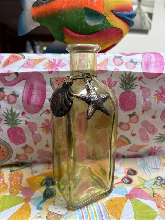 coastal-themed glass bottle vase features starfish and seashell decoration.