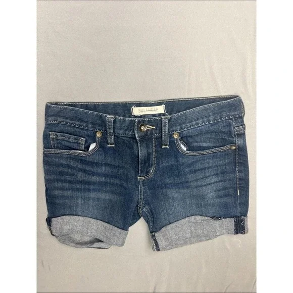 Bullhead denim shorts in a mid to dark blue wash. Rolled hem with cuffed