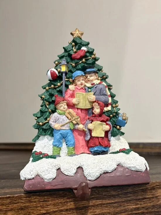 Vintage cast iron stocking holder caroling family at the tree, on a brown base