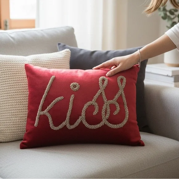 Pier 1 Imports decorative accent pillow w/beaded lettering spelling “kiss.”