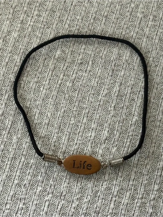 Black cord stretch bracelet w brown colored oval “Life” plaque