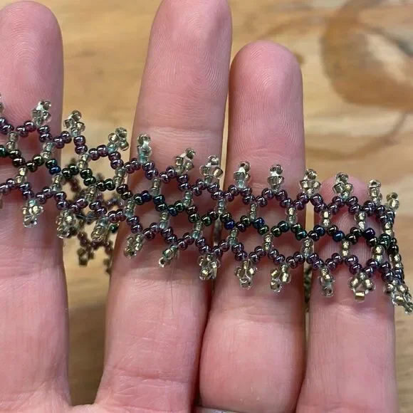 Woman’s beaded bracelet. Colors are gold,green and purple