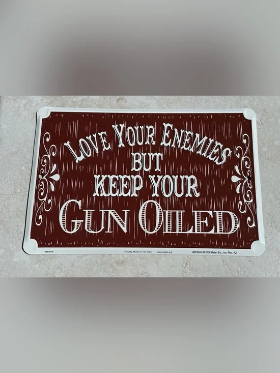 Aluminum sign “Love your enemies but keep your gun oiled”.