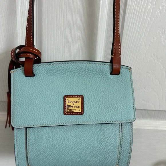 This is a Dooney & Bourke Pebble Grain East/West Flap Crossbody in a light blue