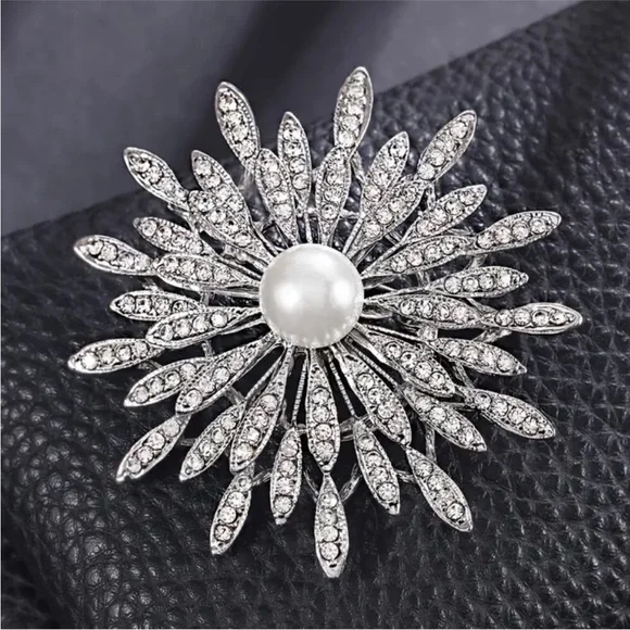 New silver-toned sunburst brooch clear rhinestones and a central faux pearl