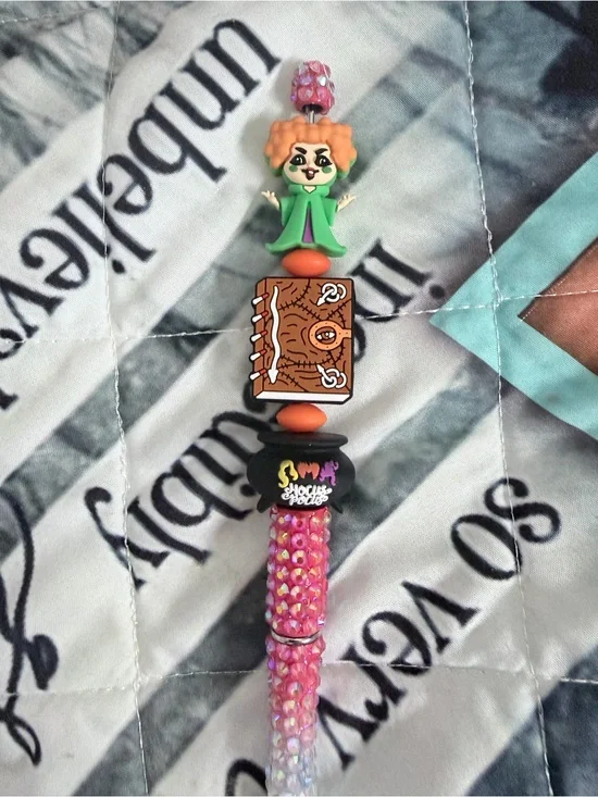 Hocus Pocus beaded pen with red-haired green witch, cauldron and book.