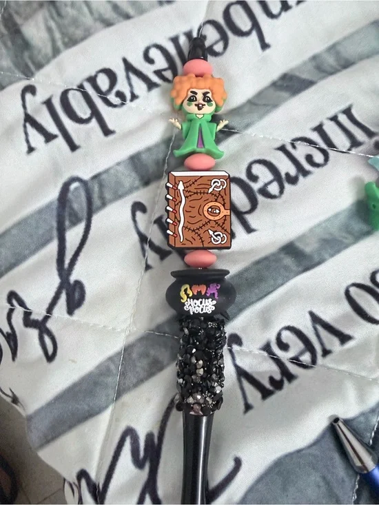Hocus Pocus beaded pen with red haired witch, book, and cauldron.